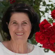 Gerlinde Maier lächelt neben roten Rosen