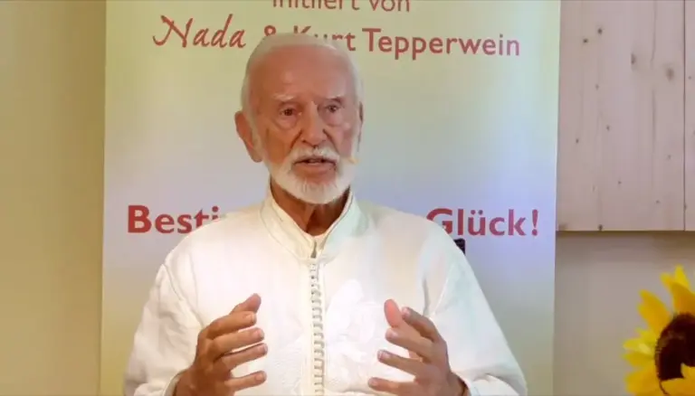 Kurt Tepperwein in weißem Gewand gestikuliert vor einem Banner mit der Aufschrift „Nada & Kurt Tepperwein“