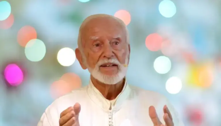 Kurt Tepperwein in weißem Gewand spricht vor einem Hintergrund aus bunten Lichtpunkten