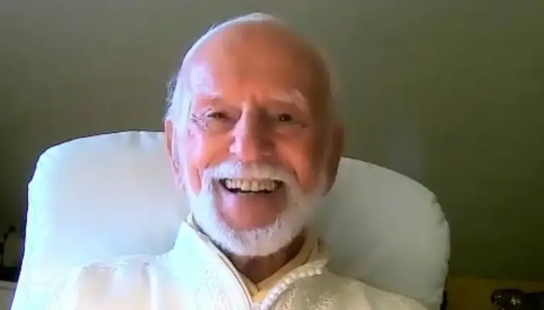 Kurt Tepperwein lacht herzlich, in einem hellen Sessel sitzend